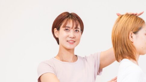 お客様の頭の位置を整えて姿勢をチェックするインストラクター